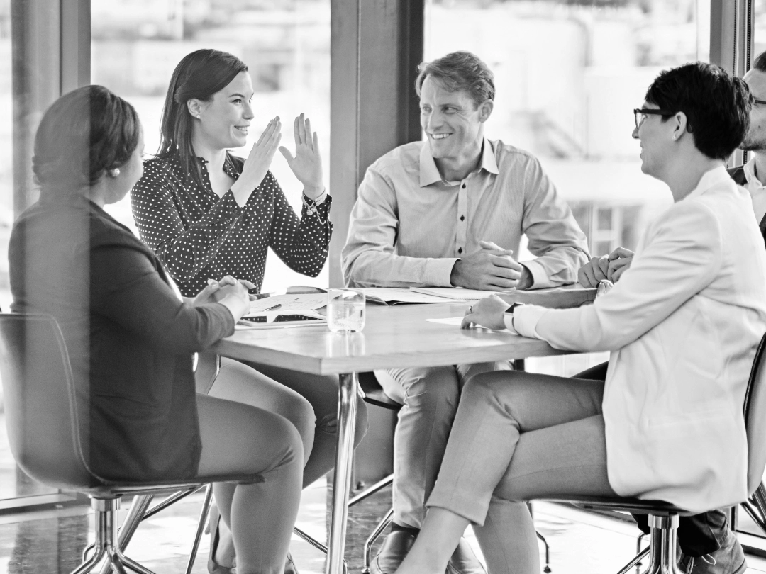 Five people gathered around a table having a positive discussion